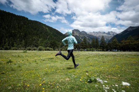 Téléchargez les photos : Femme trail runner cross country en montagne fleurie en haute altitude - en image libre de droit