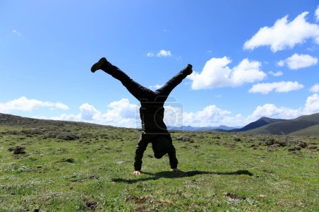 Foto de Mujer excursionista haciendo un soporte de mano en el prado de montaña de gran altitud - Imagen libre de derechos