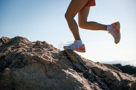 Photo for Runner legs running on sunrise seaside rocks - Royalty Free Image