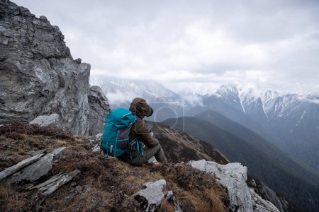 Téléchargez les photos : Une randonneuse réussie utilise le téléphone mobile au sommet d'une montagne au Tibet - en image libre de droit