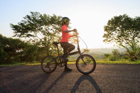 Téléchargez les photos : Monter vélo pliant sur la route de montagne ensoleillée - en image libre de droit