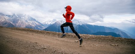 Foto de Mujer trail runner cross country running at high altitude mountains - Imagen libre de derechos