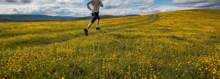 Foto de Mujer trail runner cross country running in high altitude flowering mountains - Imagen libre de derechos