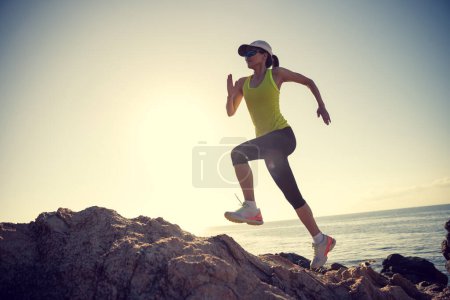 Photo for Woman runner running on sunrise seaside rocks - Royalty Free Image