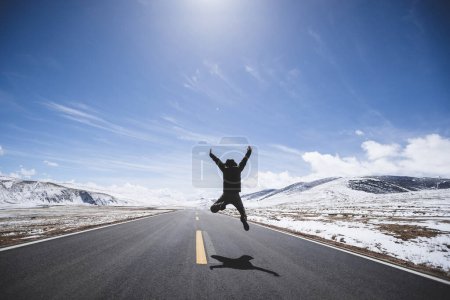 Femme asiatique sautant sur la route de pays de haute altitude