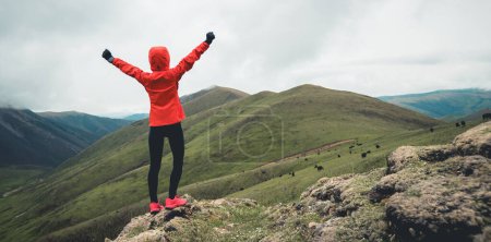 Foto de Mujer trail runner brazos abiertos en pico de montaña de gran altitud - Imagen libre de derechos