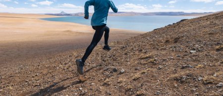 Téléchargez les photos : Femme coureuse de trail cross country courant dans les montagnes au bord du lac - en image libre de droit