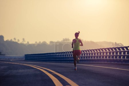 Foto de Corredor de fitness mujer corriendo en puente junto al mar - Imagen libre de derechos