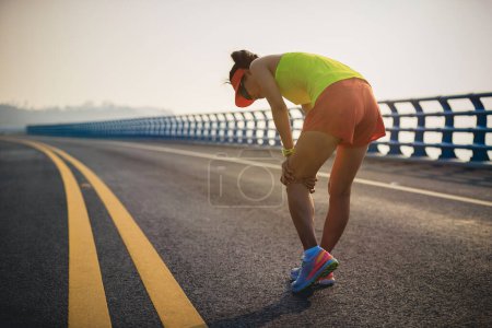 Photo for Running sport injury female runner touching her knee - Royalty Free Image