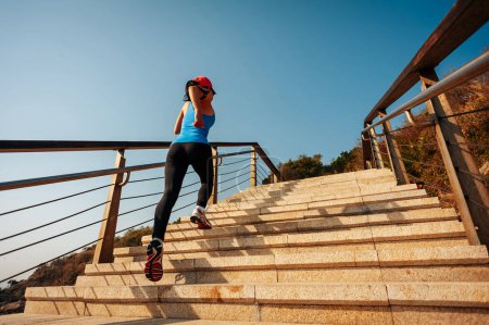 Photo for Healthy lifestyle sports woman running up on stone stairs at sunrise seaside - Royalty Free Image