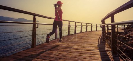 Photo for Healthy lifestyle sports woman running on wooden boardwalk seaside - Royalty Free Image