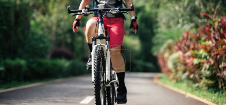 Femme vélo sans tenir le guidon sur le sentier du parc tropical d'été  