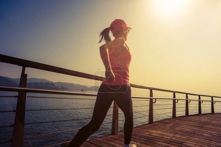 Téléchargez les photos : Mode de vie sain sport femme courir sur la promenade en bois bord de mer - en image libre de droit