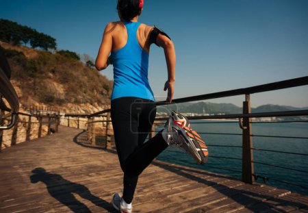 Foto de Estilo de vida saludable mujer deportiva corriendo en el paseo marítimo de madera - Imagen libre de derechos