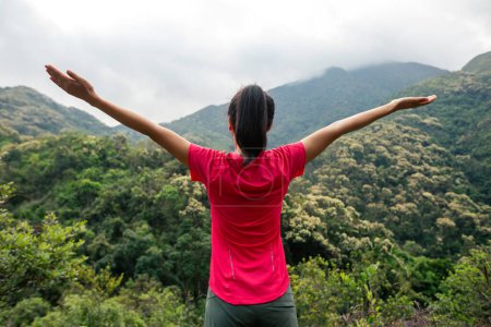 Cheering femme heureuse se sentir libre sur le sommet de la montagne du printemps matin
