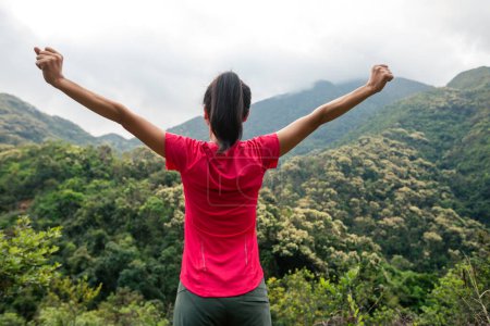Cheering femme heureuse se sentir libre sur le sommet de la montagne du printemps matin