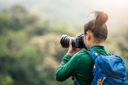 Téléchargez les photos : Femme photographe prenant des photos sur le sommet de la montagne de printemps - en image libre de droit