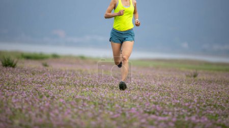 Femme coureur courir dans les fleurs de printemps