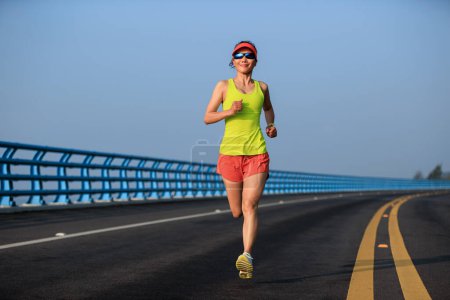 Foto de Corredor de fitness mujer corriendo en puente junto al mar - Imagen libre de derechos