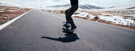 Skateboard skateboard sur route de campagne enneigée