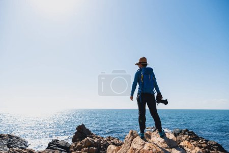 Foto de Mujer fotógrafa disfrutar de la vista al amanecer rocas junto al mar - Imagen libre de derechos