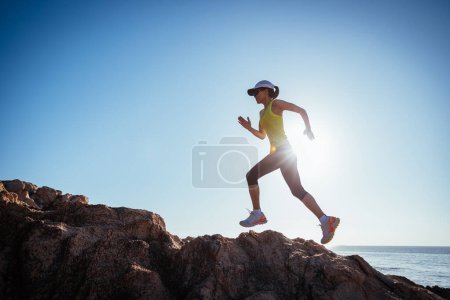 Téléchargez les photos : Femme coureuse qui court sur les rochers du lever du soleil - en image libre de droit