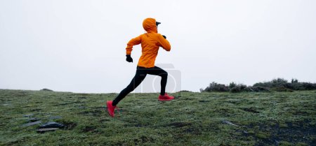Foto de Mujer trail runner cross country running to high altitude mountain peak - Imagen libre de derechos