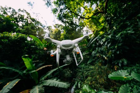 Téléchargez les photos : Drone blanc avec caméra volant dans la forêt d'été - en image libre de droit