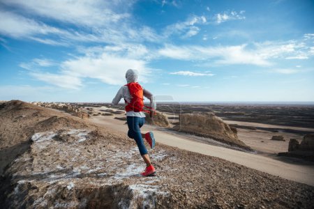 Téléchargez les photos : Femme coureuse de trail cross country courir sur le sommet d'une colline déserte - en image libre de droit