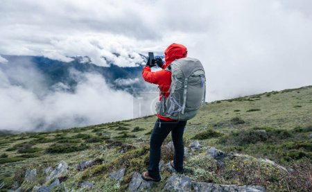 Foto de Senderismo uso de la mujer teléfono inteligente tomar fotos en las montañas de gran altitud - Imagen libre de derechos