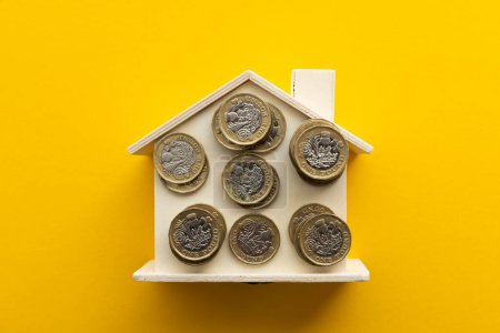 Téléchargez les photos : Le coût de la vie. Royaume-Uni pièces de monnaie sur une maison en bois. - en image libre de droit