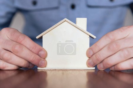 Téléchargez les photos : Hale mains tenant une petite maison en bois. Concept de marché immobilier. - en image libre de droit