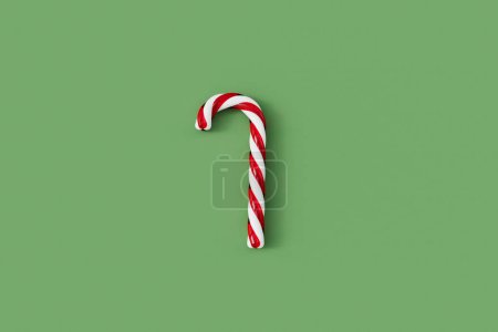 Foto de Caña de caramelo de Navidad rojo y blanco dulce festivo sobre un fondo verde. Renderizado 3D - Imagen libre de derechos