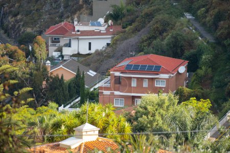 Foto de Paneles solares sobre techos de casas en un pueblo. Alrededor de la vegetación. Ecología, energía verde, salvar el planeta. - Imagen libre de derechos