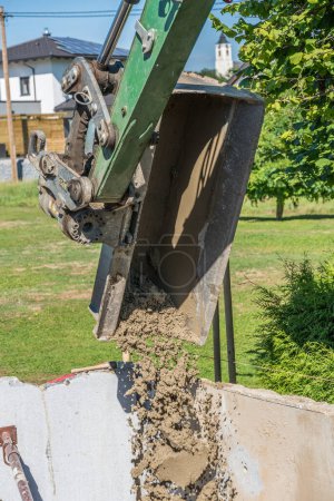 Téléchargez les photos : La pelle de la machine de construction aide au bétonnage sur le chantier - en image libre de droit
