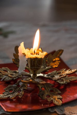 Photo for Atmospheric light from a burning candle in a brass candle holder - Royalty Free Image