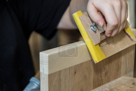 Holz mit Schleifpapier auf dem Schleifblock als Werkzeug schleifen