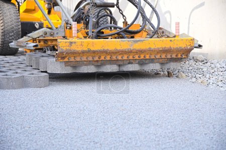 Laying concrete lawn pavers for driveway with construction machine