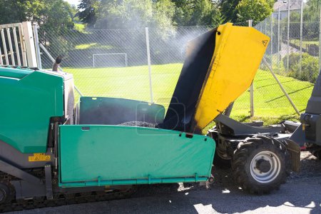 Foto de Trabajos de asfalto con máquina de construcción pavimentadora y volquete - camión volquete de primer plano - Imagen libre de derechos
