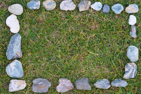 rectangular frame made of stones in green meadow - background