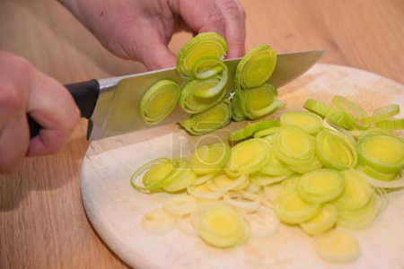 Person cuts leeks in the kitchen - close-up reshly cut leeks