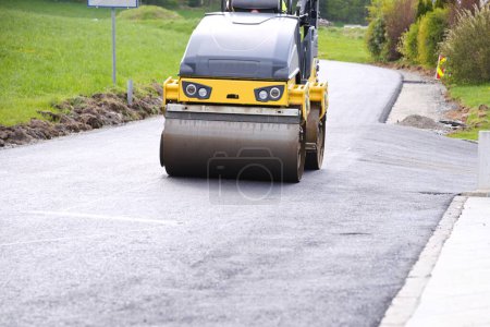 Foto de Utilice un rodillo de carretera para compactar asfalto fresco en el sitio de construcción mediante vibración - Imagen libre de derechos