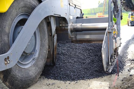 Asphalting a road with paver - close-up asphalt paver, tar