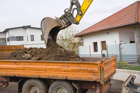 Baggerschaufel hebt Erde und LKW auf Baustelle aus - Nahaufnahme
