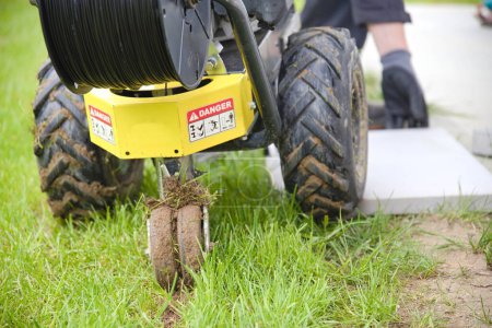 Gärtner mit Kabelverlegemaschine verlegt Grenzdraht für Rasenmäherroboter - Nahaufnahme