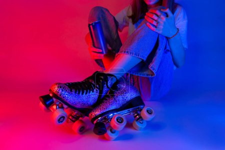 Téléchargez les photos : Roller skater tenant une boisson gazeuse dans une boîte pendant le repos. Patinage - sports et loisirs. Affiche de style pop art saturée rose et bleu. - en image libre de droit