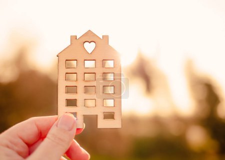 Téléchargez les photos : Hand holding wooden model of the house. Real estate, insurance and mortgage loans related concept. - en image libre de droit