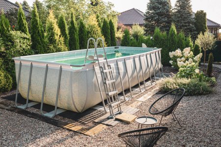 Photo for Relaxation corner in the garden. Above ground, rectangular, rack (frame) swimming pool outdoor in the pebble (gravel) nook. Summer holiday (vacation) and recreation. - Royalty Free Image