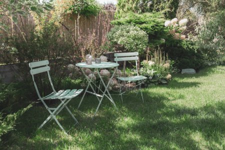 Photo for Peaceful, cozy garden corner with a pastel mint table, chairs and white hydrangea flowers. Gardening and landscape design - french style, romantic relaxation nook. - Royalty Free Image
