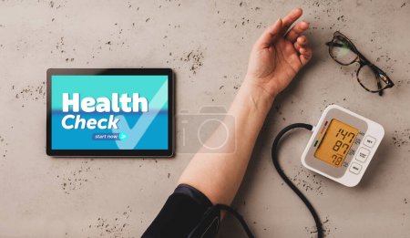 Medicina: el paciente comienza la revisión de salud en línea (encuesta) mientras usa el monitor automático de presión arterial. Tableta con diseño de contenido confeccionado, ilustrativo y de servicio médico.